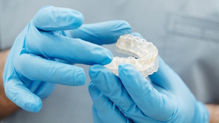 Close-up of a dentist holding a 3D printed tooth model
